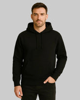 Man wearing a black hoodie against a beige background
