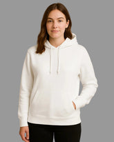 Person wearing a white hoodie against a beige background