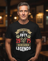 Man wearing a black t-shirt with a celebratory design in a bar setting