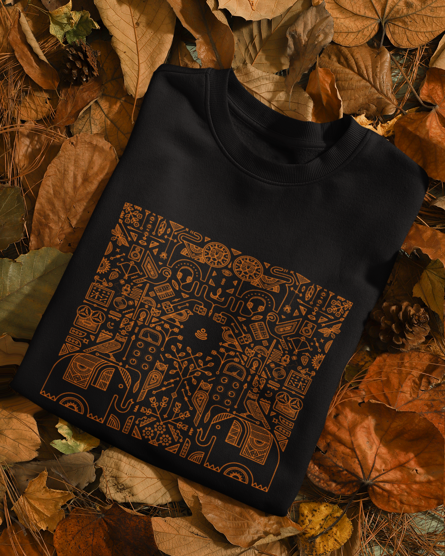 Black sleeveless sweater with a pattern on a bed of autumn leaves