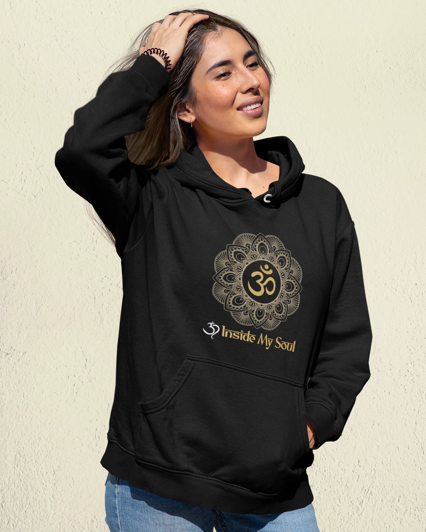 Person wearing a black hoodie with a symbol and text on a beige background