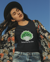 Woman wearing a black t-shirt with a graphic design and text, standing outdoors against a clear blue sky.