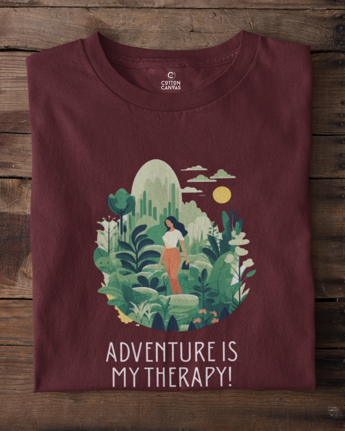 Maroon t-shirt with nature-themed design and 'Adventure is My Therapy!' text on a wooden background