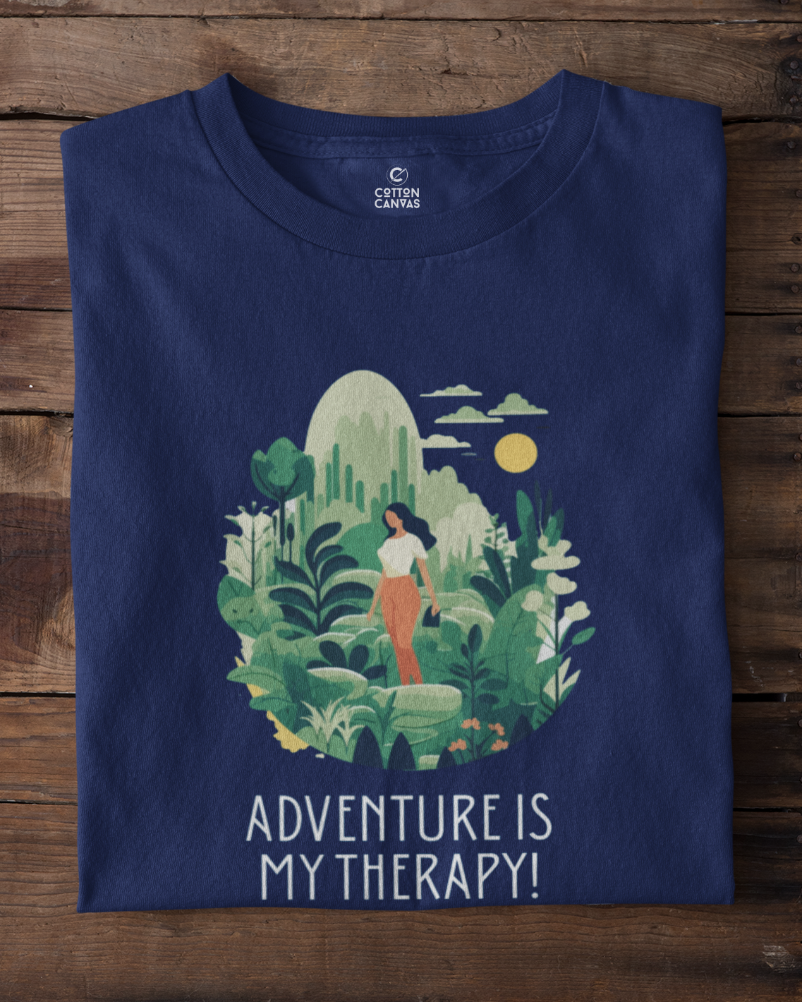 Navy blue t-shirt with a nature-themed graphic and 'Adventure is My Therapy!' text on a wooden surface.