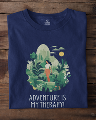 Navy blue t-shirt with a nature-themed graphic and 'Adventure is My Therapy!' text on a wooden surface.