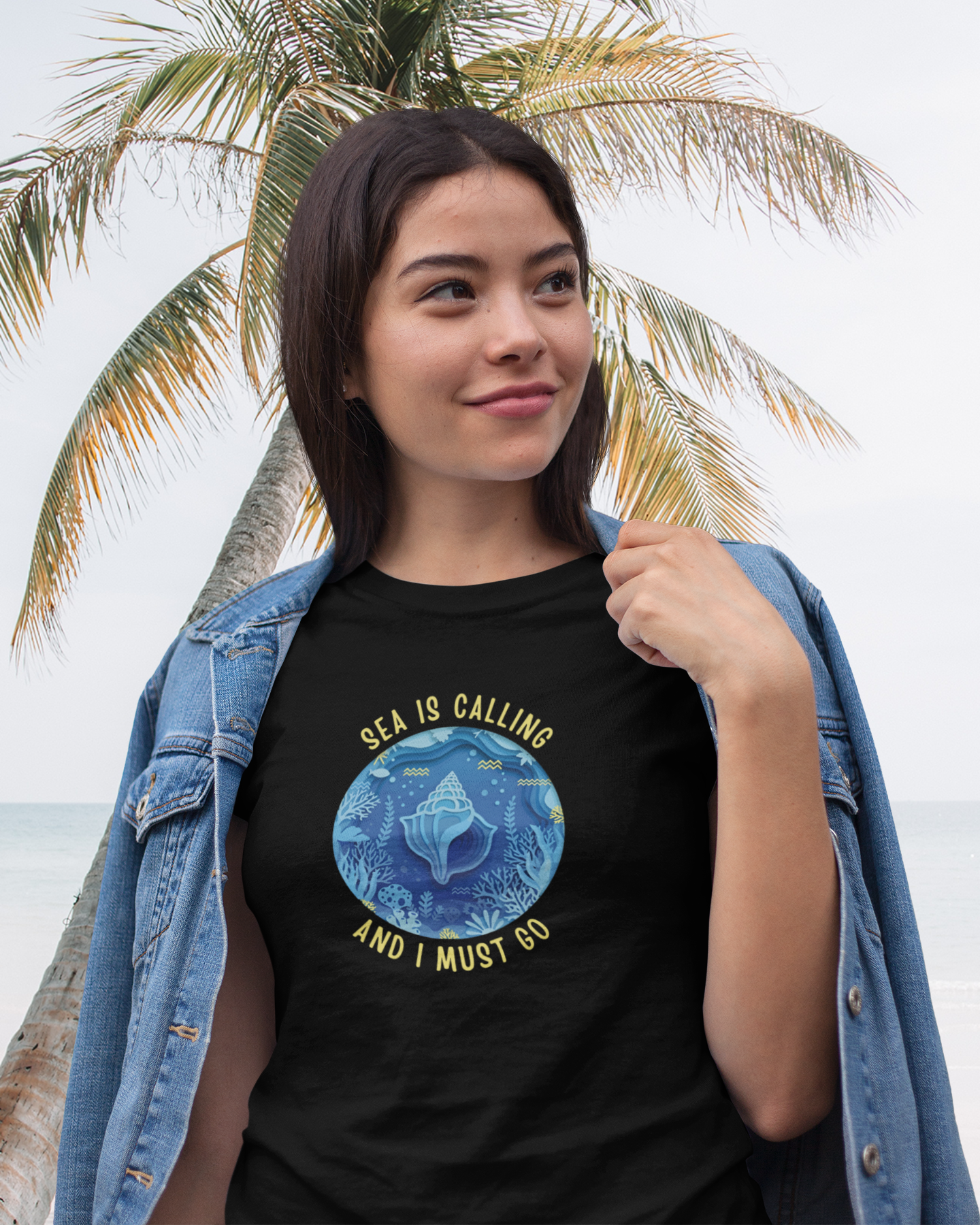 Woman wearing a black t-shirt with a blue graphic and text, standing in front of a palm tree.