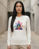 Woman wearing a white long-sleeve shirt with a colorful chakra design in an indoor setting.