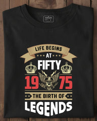 Black t-shirt with 'Life Begins at Fifty 1975 The Birth of Legends' design on a wooden surface