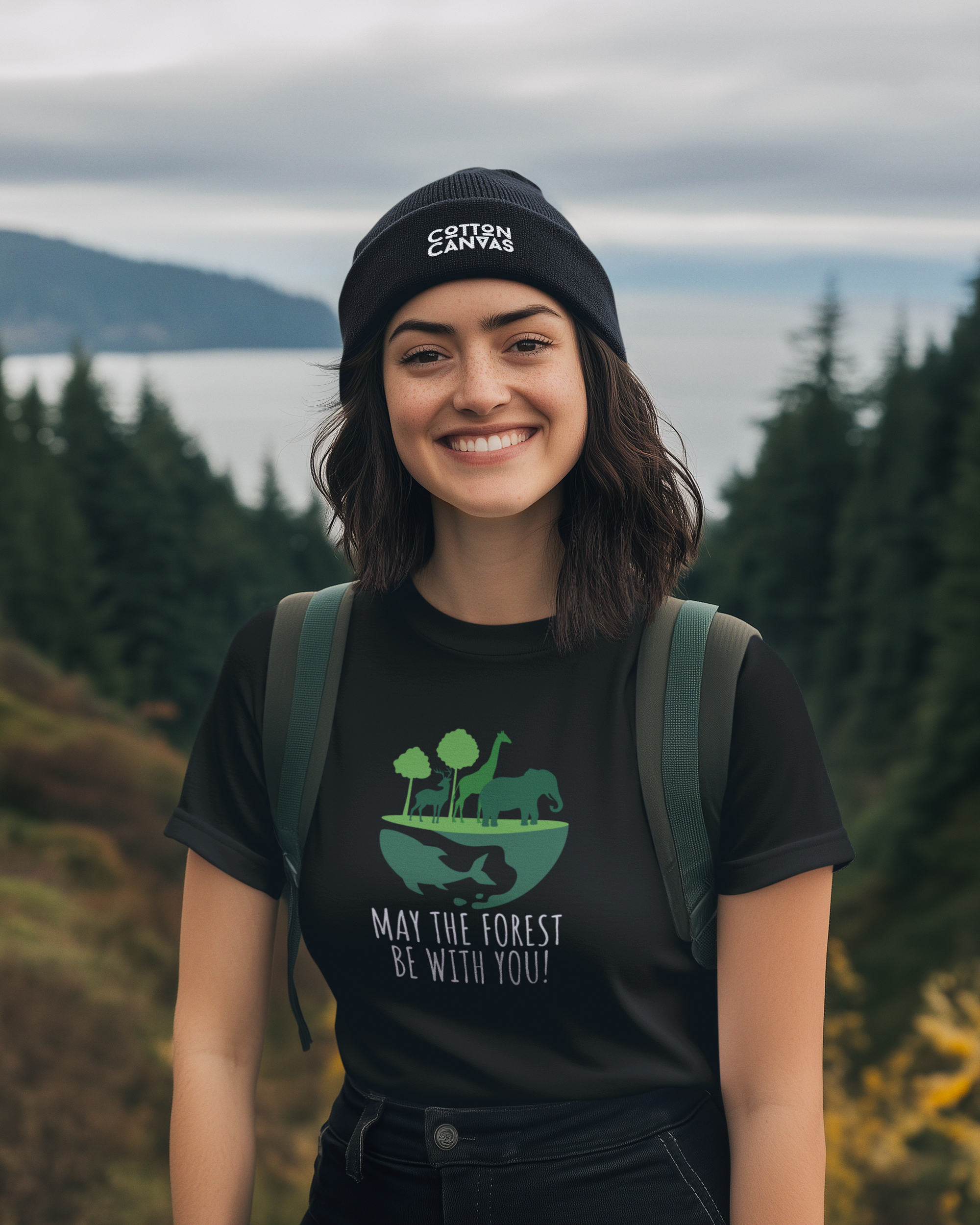 Person wearing a black t-shirt with a nature graphic and text, standing outdoors with trees and water in the background.