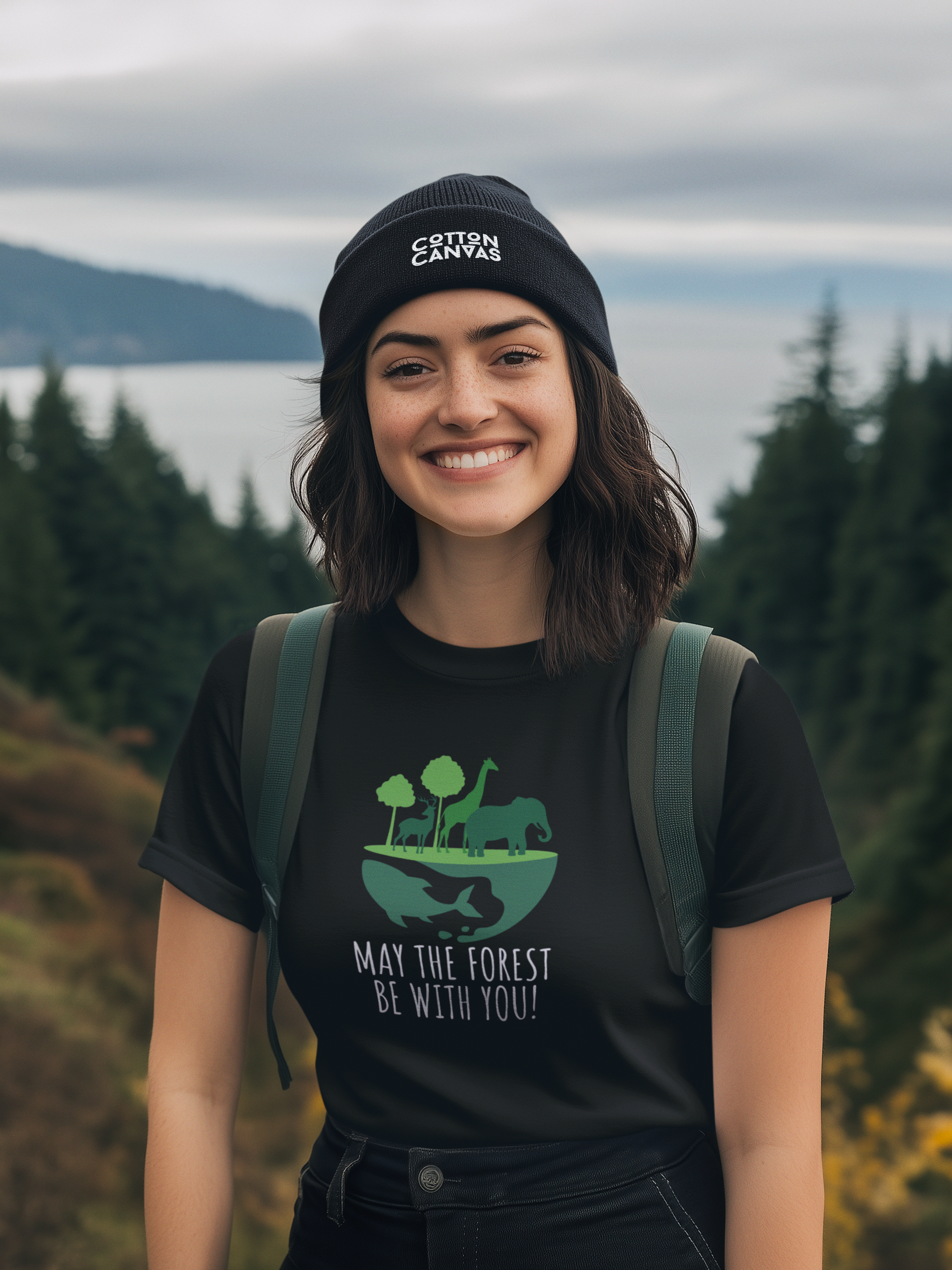 Person wearing a black t-shirt with a nature graphic and text, standing outdoors with trees and water in the background.