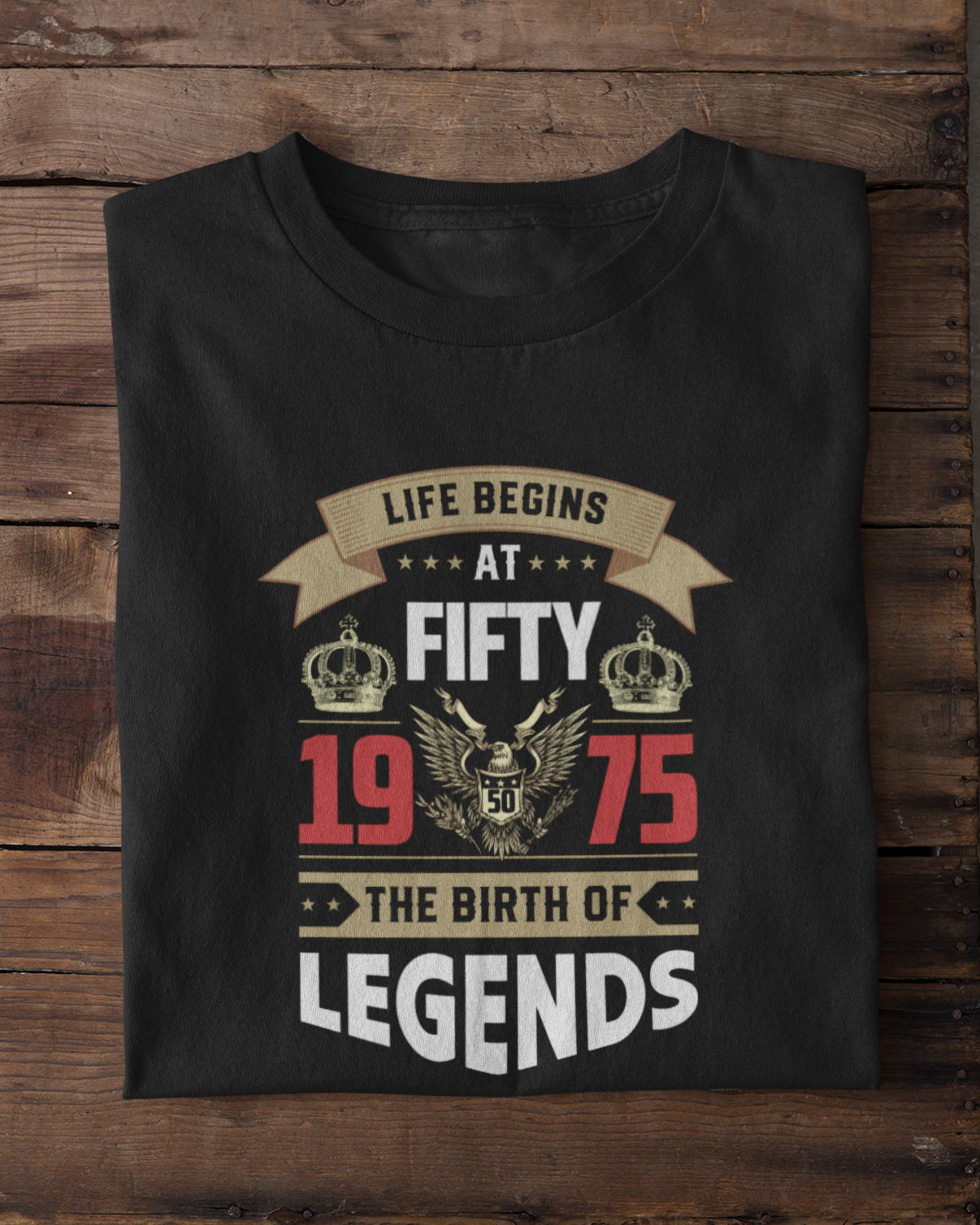 Black t-shirt with a design on a wooden surface with white sneakers in the foreground.