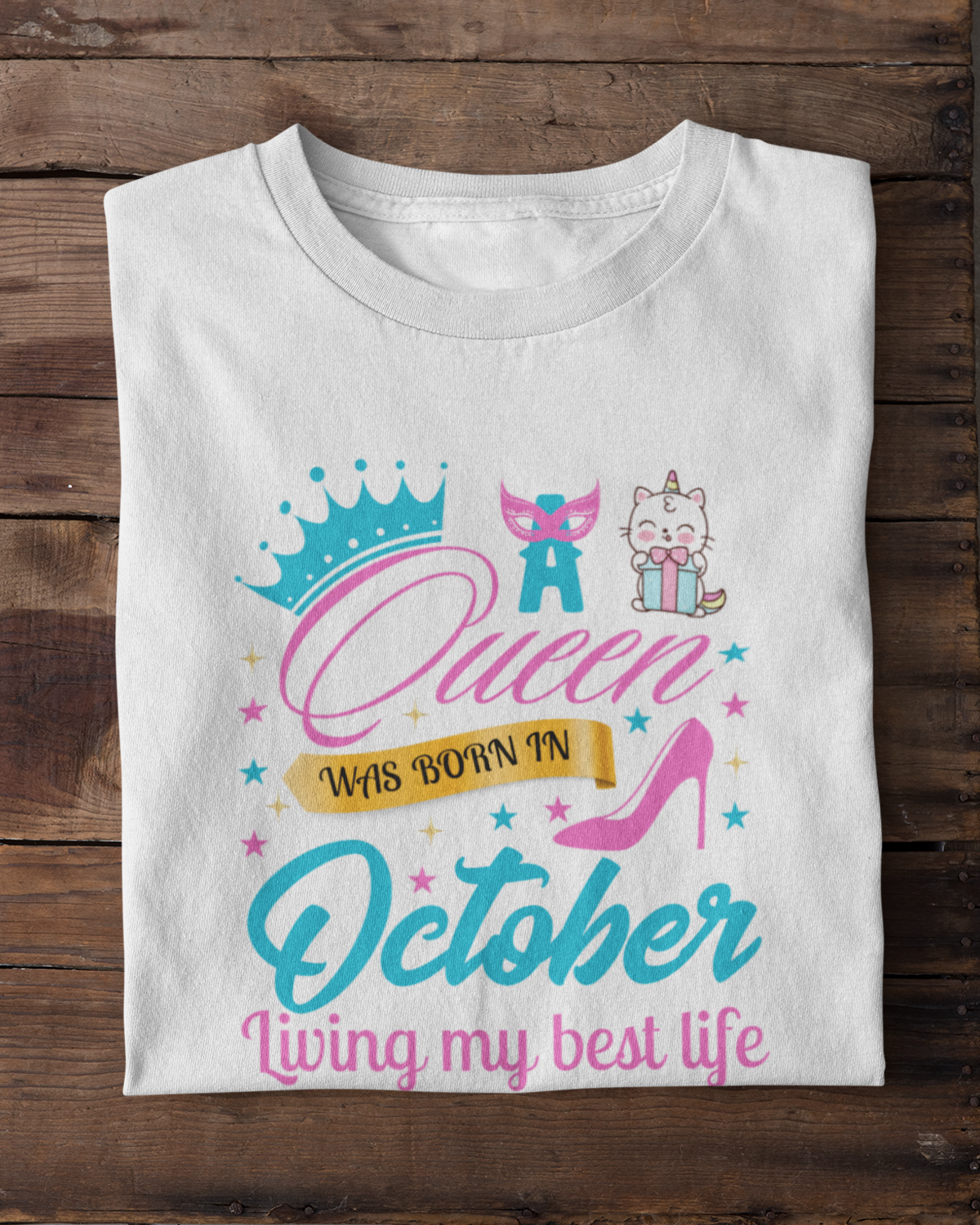 White t-shirt with colorful graphic design on a wooden surface with white sneakers.