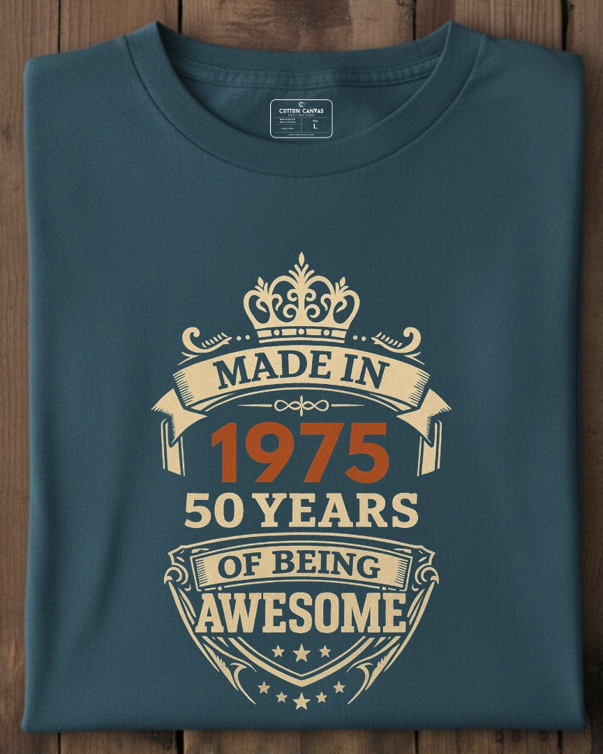 Folded blue t-shirt with 'Made in 1975, 50 years of being awesome' text on a wooden surface