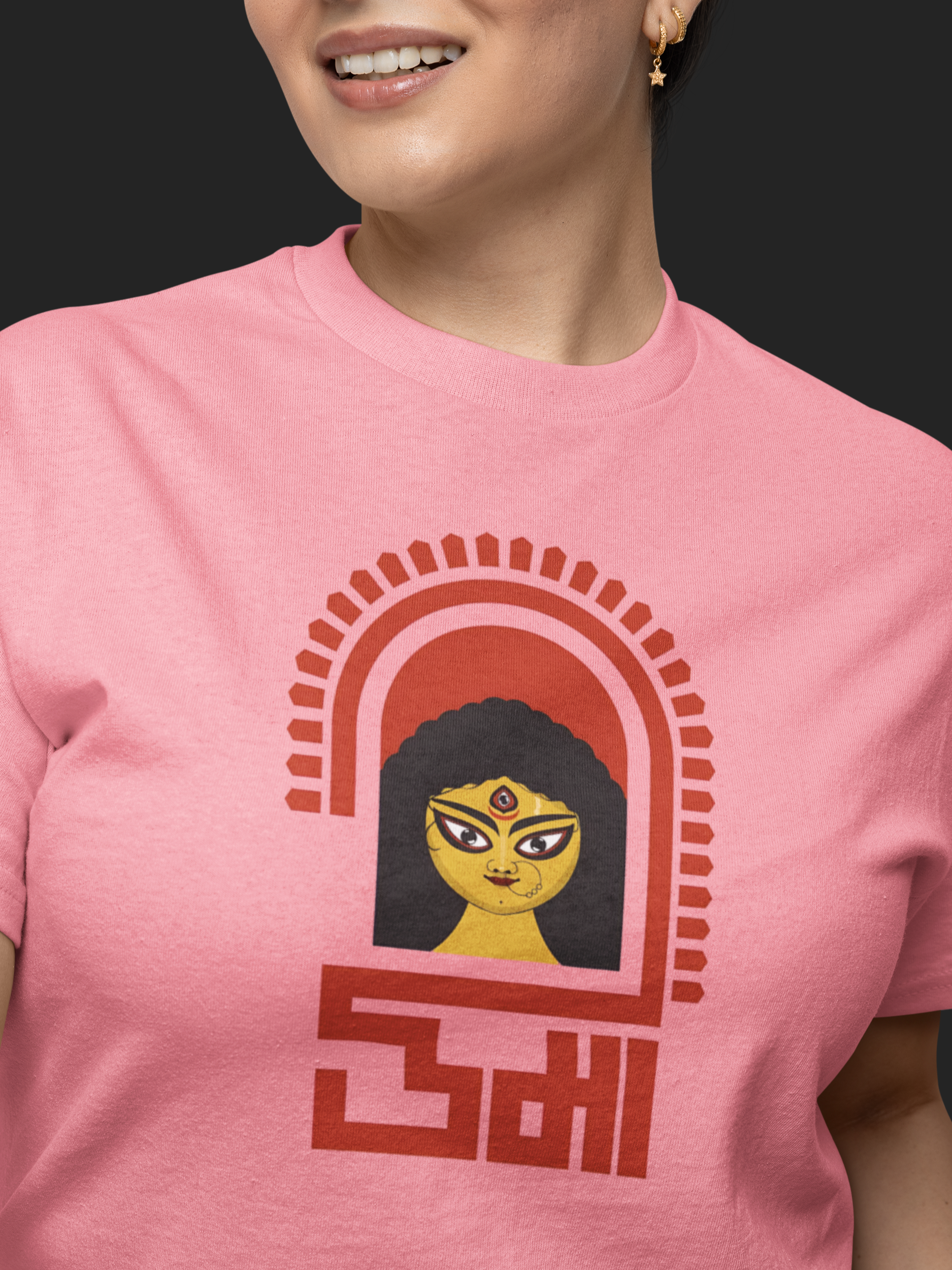 Person wearing a pink t-shirt with a graphic design on a black background