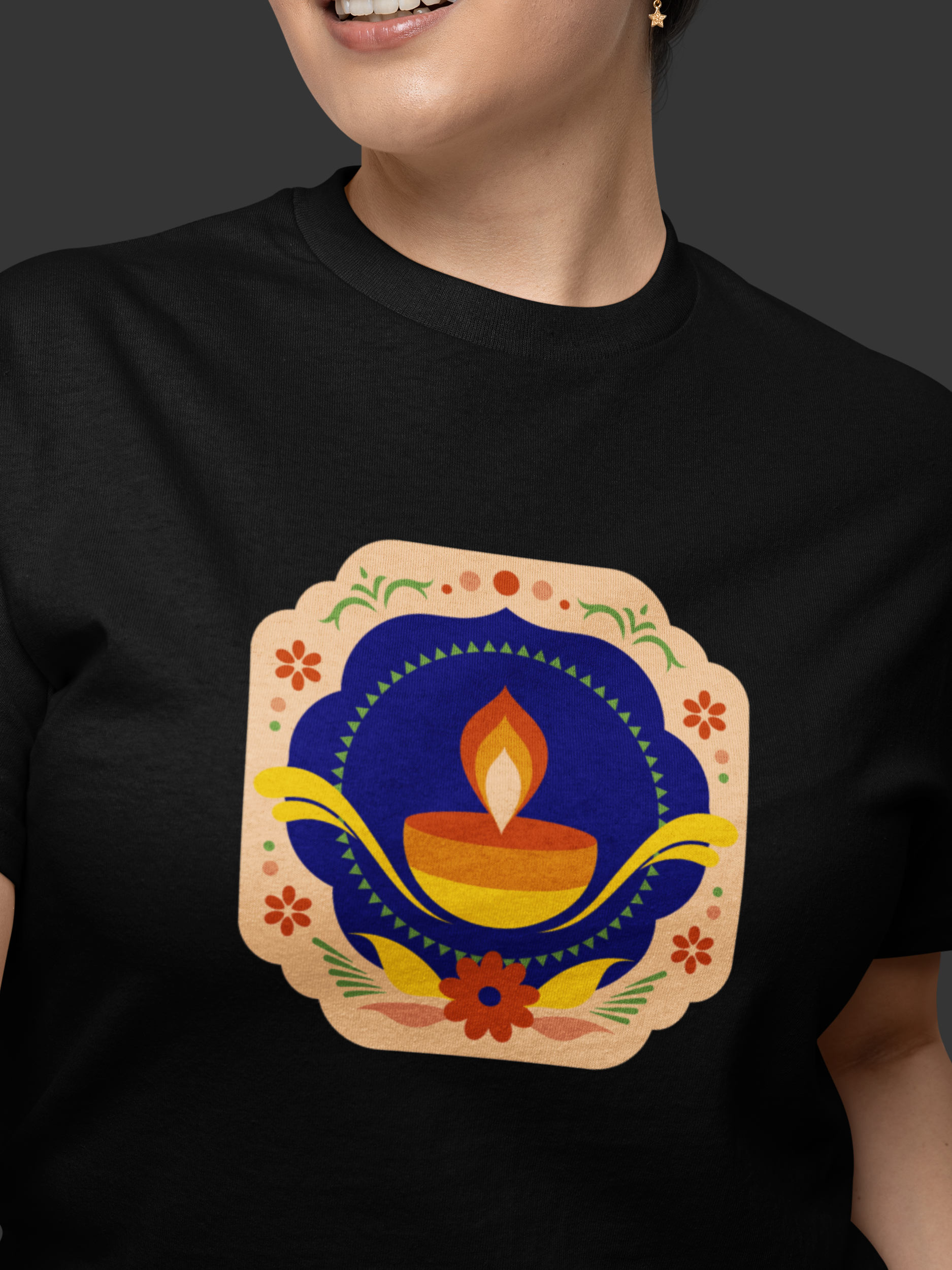 Person wearing a black t-shirt with a colorful Diwali-themed design featuring a lamp and flowers.