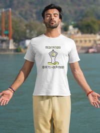 Man wearing a t-shirt with 'Meditation quiets your mind' design by a body of water.