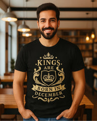 Man wearing a black t-shirt with 'Kings are born in December' design in a restaurant setting