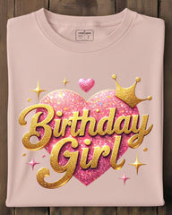Folded pink t-shirt with 'Birthday Girl' design on a wooden surface