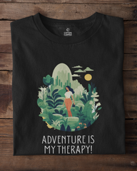 Black t-shirt with a nature-themed design and 'Adventure is My Therapy!' text on a wooden surface.