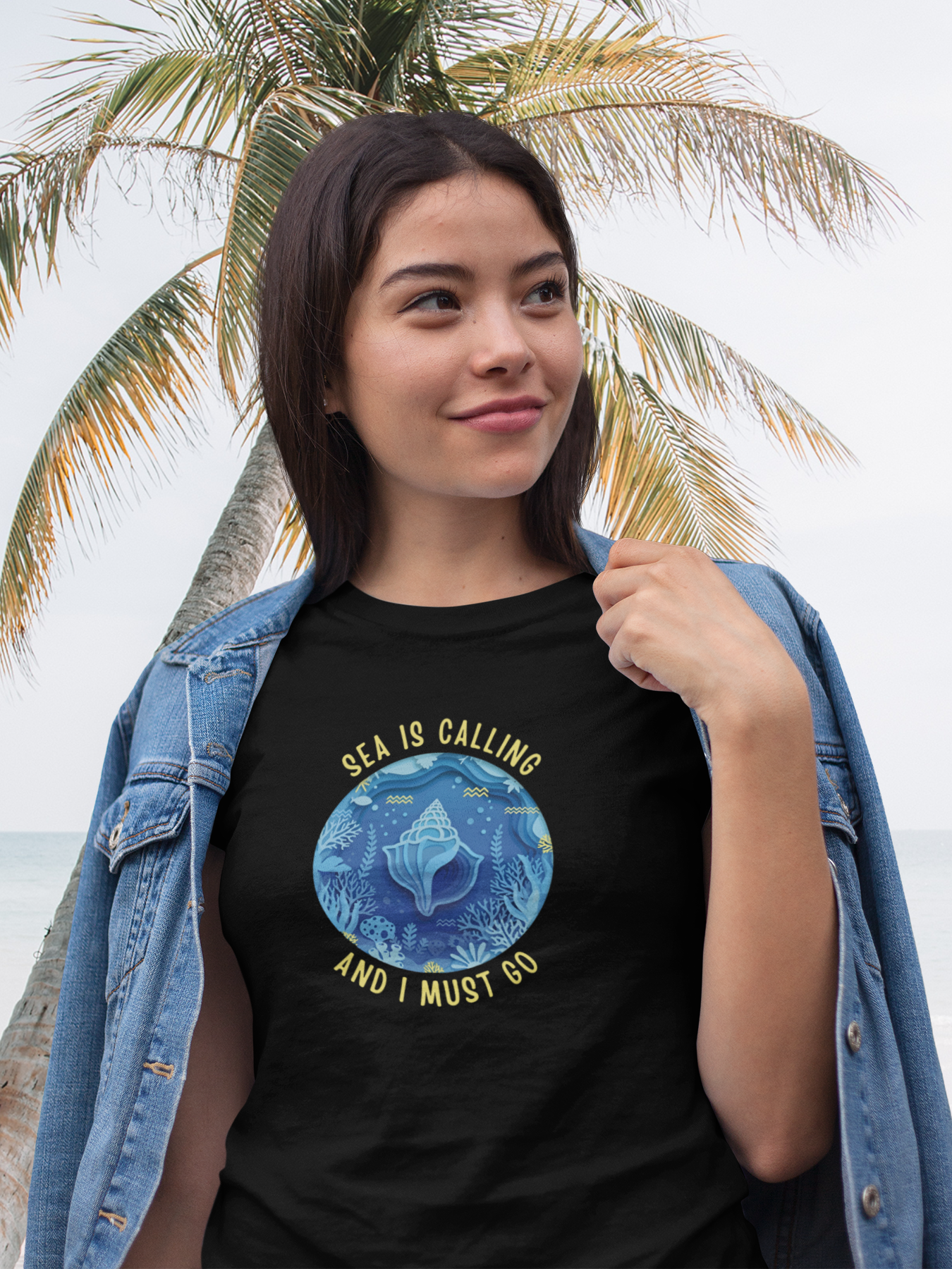Woman wearing a black t-shirt with a blue graphic and text, standing in front of a palm tree.